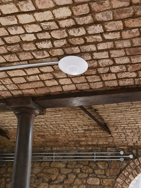 Ubiquiti UniFi commercial WiFi access point installed on a brick ceiling